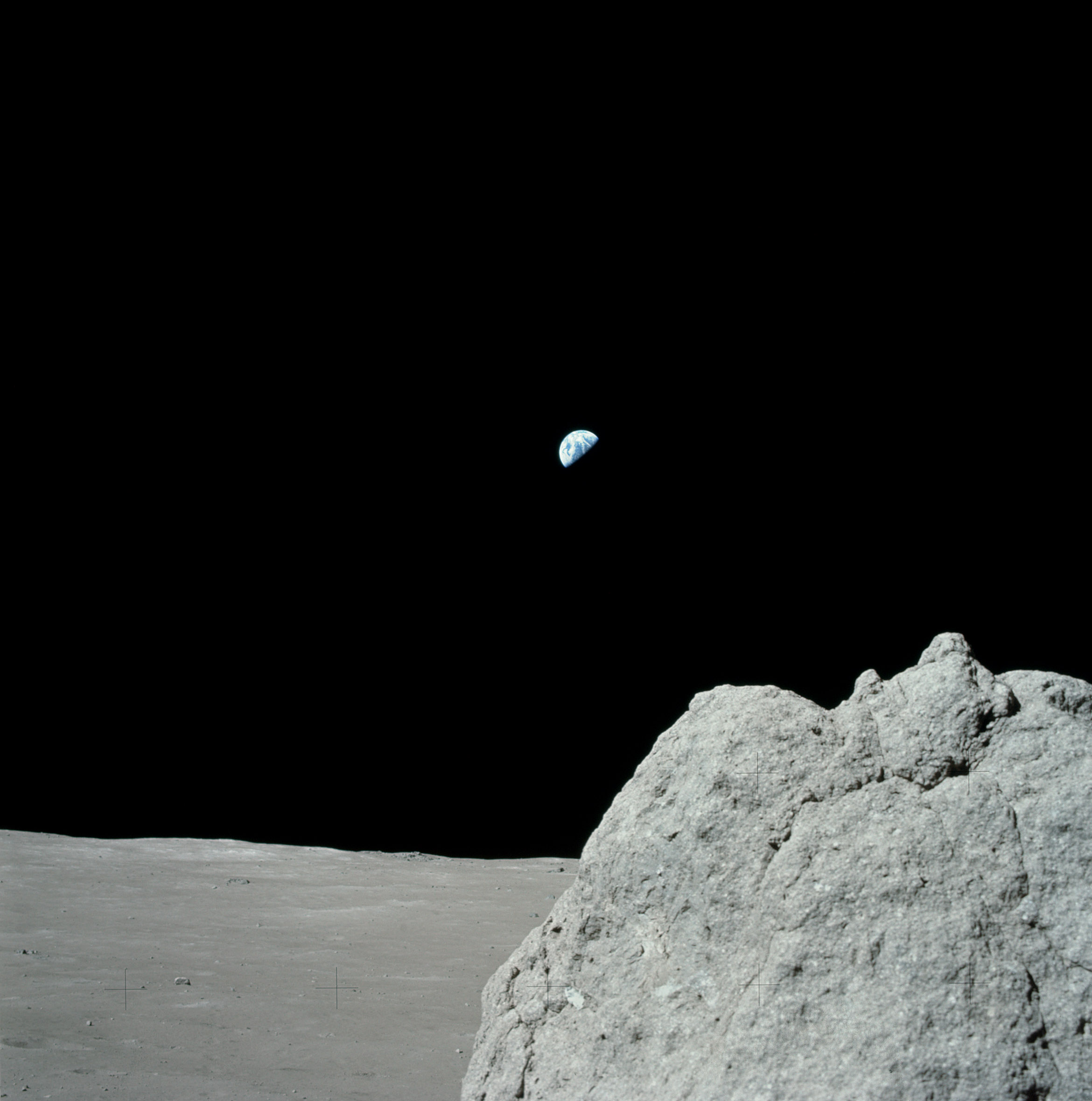 boulder on the moon with earth above